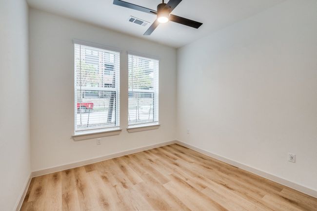 Empty room with ceiling fan, wood finished floors, visible vents, and baseboards | Image 15