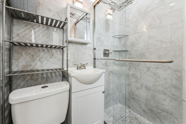 Full bathroom featuring toilet, vanity, a stall shower, and tile walls | Image 10