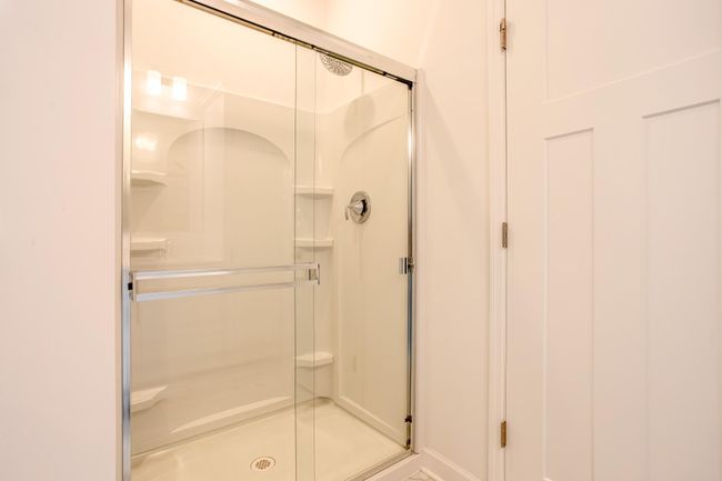 Pristine walk-in shower with sliding glass doors and built-in shelving for a clean, polished look. | Image 22