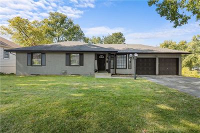 Ranch-style house with a front lawn and a garage | Image 1