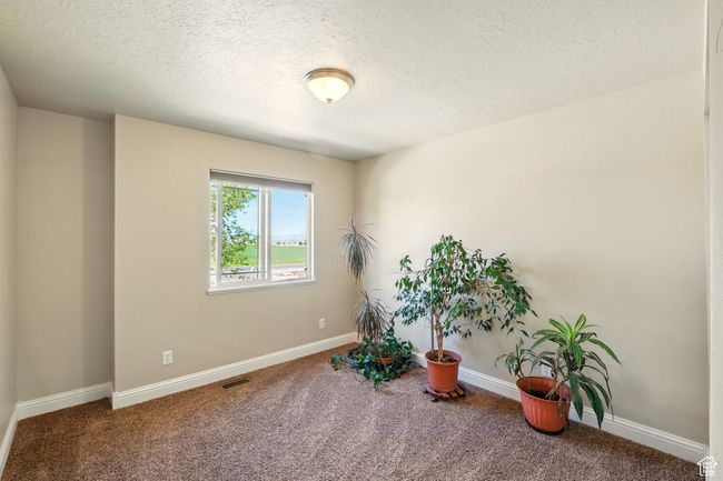 Living area with carpet flooring, a textured ceiling, and baseboards | Image 17