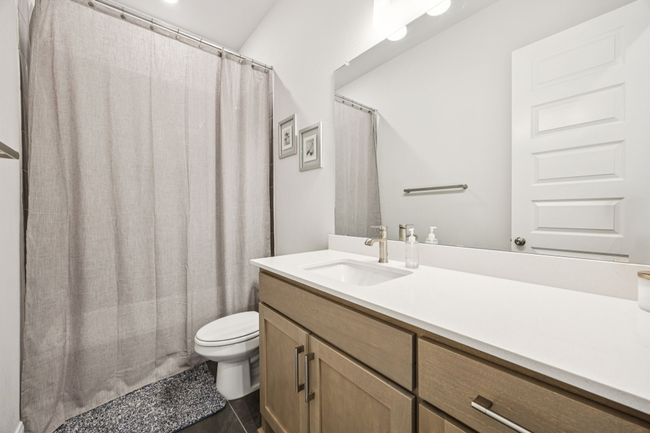 Full bathroom with vanity, toilet, and curtained shower | Image 8