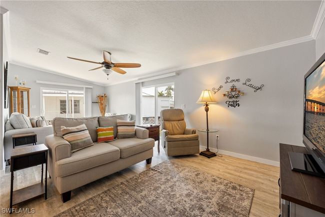 Living room featuring wood finished floors, a ceiling fan, ornamental molding, and baseboards | Image 15