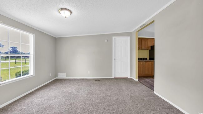 Empty room with a textured ceiling, carpet floors, and ornamental molding | Image 11