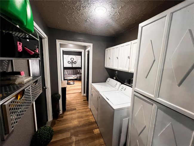Laundry room featuring cabinet space, a textured ceiling, separate washer and dryer, and dark wood-type flooring | Image 23