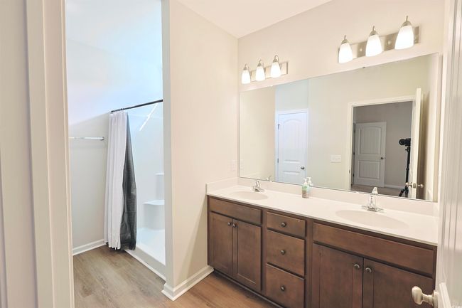 Bathroom featuring wood finished floors, double vanity, and a shower with curtain | Image 14