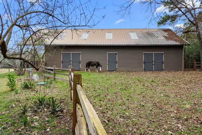 Charming Dutch doors allow fresh air to circulate in the stall and barn and enable the horses to socialize with one another when inside the stall. Split rail fencing for turnout provides plenty of space for grazing, riding and socializing as well. | Image 45