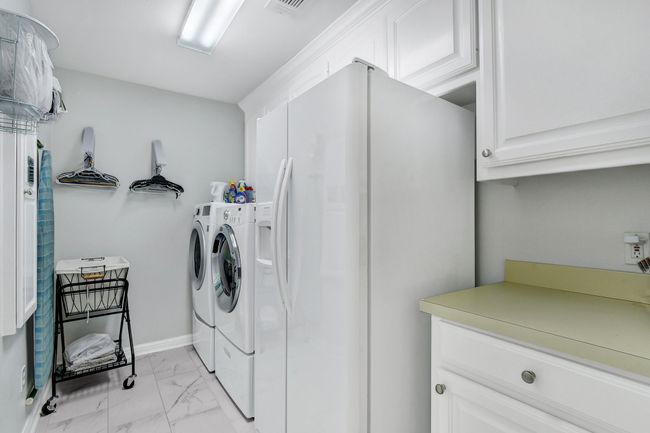 Laundry area with cabinet space, separate washer and dryer, and light marble finish floors | Image 17