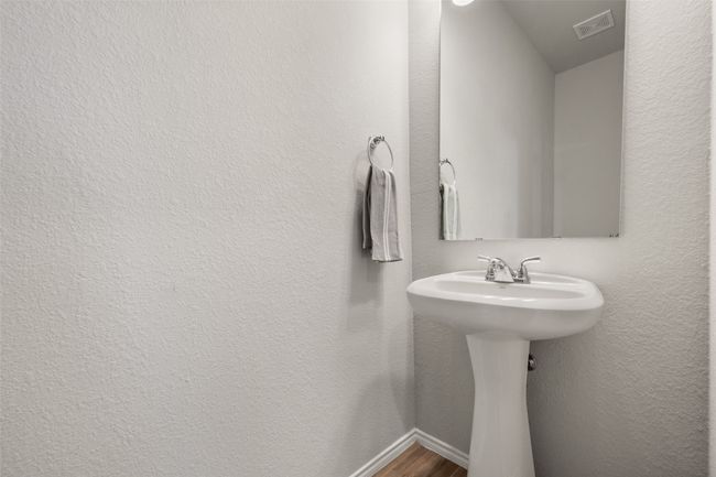 Bathroom with visible vents, baseboards, wood finished floors, a sink, and a textured wall | Image 25
