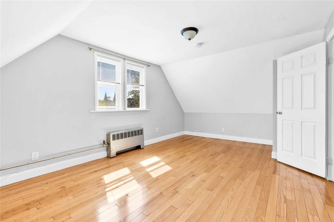 Additional living space featuring radiator, vaulted ceiling, light wood-style flooring, and baseboards | Image 10