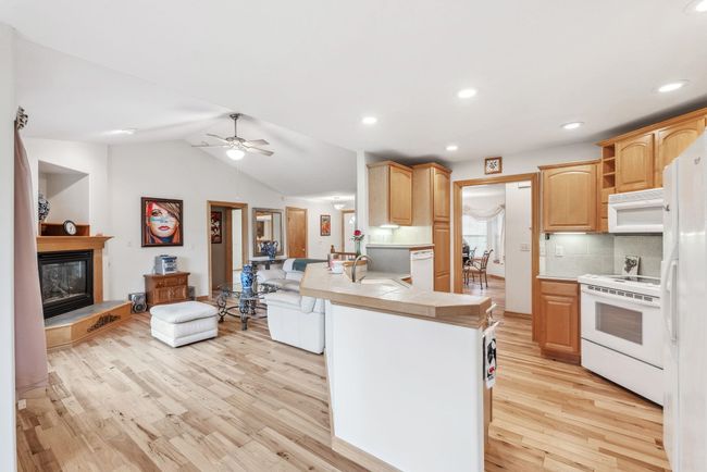 Kitchen featuring white appliances, a peninsula, light wood-style flooring, open floor plan, and ceiling fan | Image 6