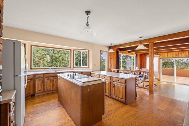 Kitchen with freestanding refrigerator, a kitchen island, electric cooktop, light wood-style floors, and light countertops | Image 9