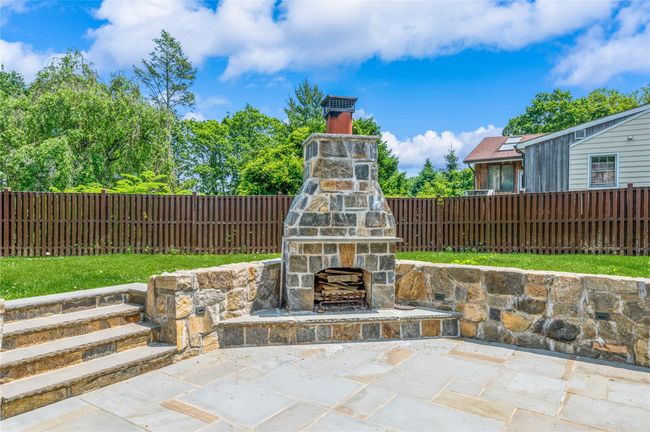 Fenced backyard featuring an outdoor stone fireplace and a patio area | Image 19