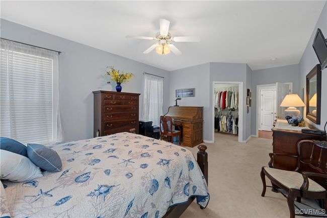 Bedroom with light colored carpet, a walk in closet, a closet, a ceiling fan, and multiple windows | Image 27