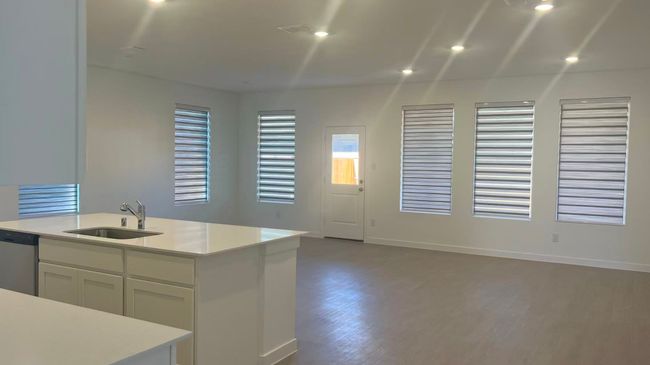 Kitchen featuring white cabinetry, stainless steel dishwasher, dark wood-type flooring, open floor plan, and light stone counters | Image 9
