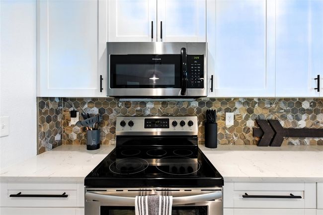 Custom backsplash adds a modern edge with mixed tones and texture—definitely not your standard white subway tile. It's a statement piece that elevates the whole kitchen | Image 24