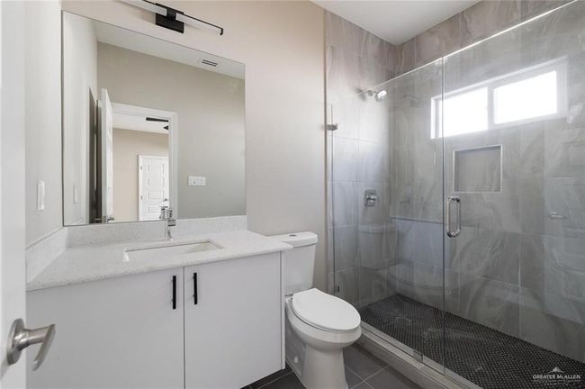 Bathroom featuring a shower stall, toilet, tile patterned flooring, and vanity | Image 7