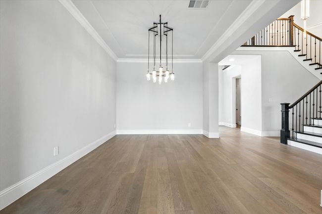 Unfurnished dining area featuring stairs, wood finished floors, crown molding, and a chandelier | Image 8