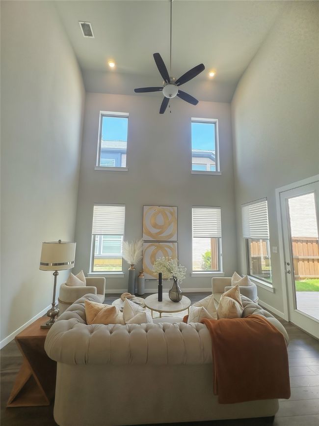 Living room with a towering ceiling, wood finished floors, plenty of natural light, a ceiling fan, and baseboards | Image 11
