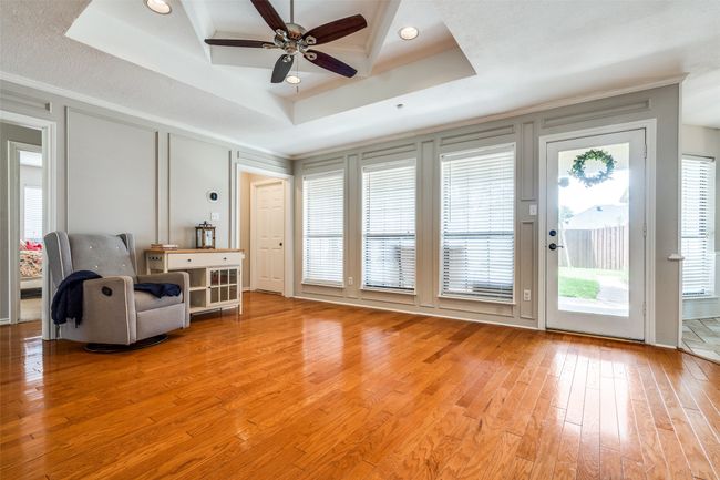 Living area featuring a raised ceiling, light wood-type flooring, ceiling fan, and ornamental molding | Image 11