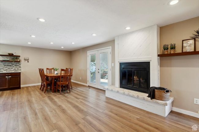 Dining area with french doors, wood LVP floors, recessed lighting, a fireplace, and a floating shelf. | Image 4
