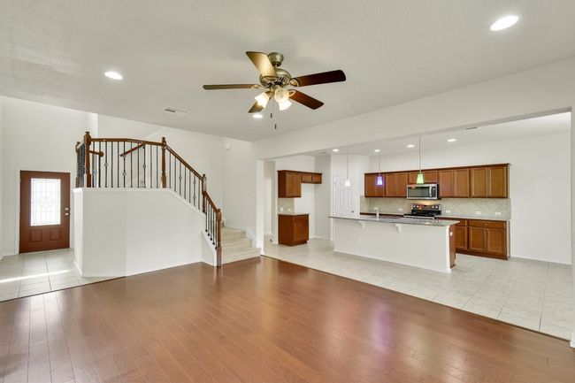 Unfurnished living room featuring stairway, a ceiling fan, light wood-style flooring, visible vents, and recessed lighting | Image 8