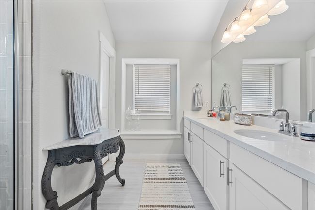 Full bathroom with double vanity, baseboards, a tile shower, and wood finished floors | Image 22