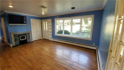 Unfurnished living room with wood-type flooring, ornamental molding, and a baseboard heating unit | Image 2