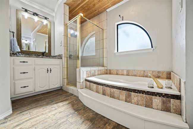 Full bathroom featuring a bath, ornamental molding, a shower stall, vanity, and wood finished floors | Image 18