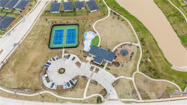 In addition to the pools, the neighborhood clubhouse offers a variety of other amenities to enjoy. There are two tennis courts, perfect for friendly matches or practice sessions. A fun splash pad provides a cool, interactive space for kids to enjoy water play during warm days. The playground offers a safe and exciting environment for children to climb, swing, and explore. For outdoor activities, a large grassy open space is available, ideal for picnics, sports, or simply relaxing in the sun. | Image 24
