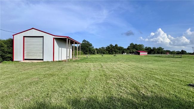 View of grassy yard with an outbuilding, a garage, and a rural view | Image 8