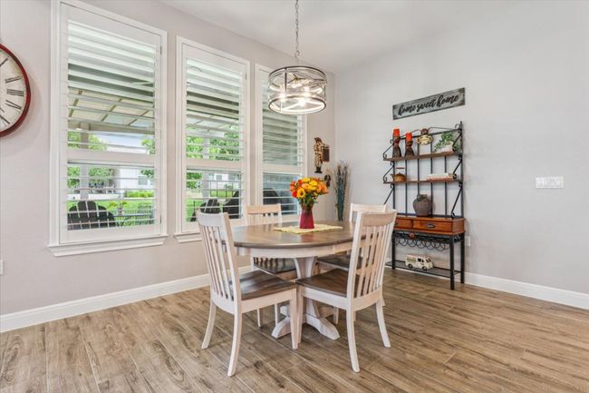 Breakfast area with wood look tile flooring and a chandelier. Window overlooks the nicely landscaped backyard | Image 17