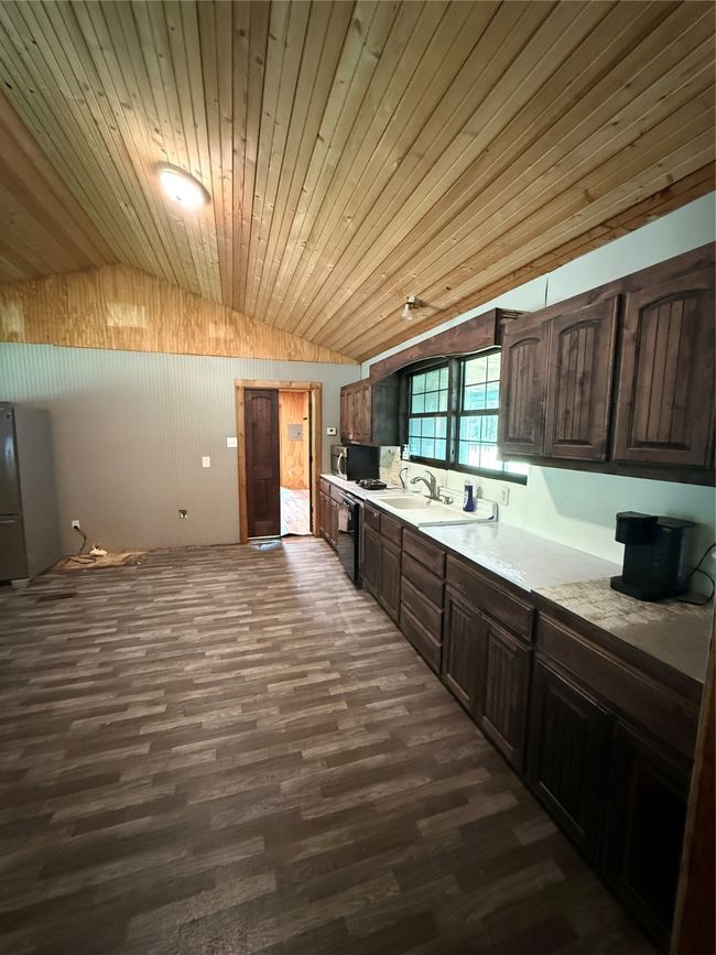 Kitchen with vaulted ceiling, dark wood-style floors, light countertops, dark brown cabinetry, and a sink | Image 20