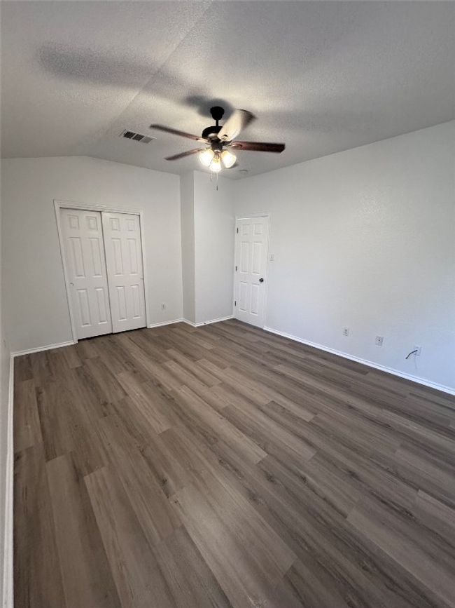 Unfurnished bedroom featuring dark wood-type flooring, a textured ceiling, a closet, and ceiling fan | Image 32