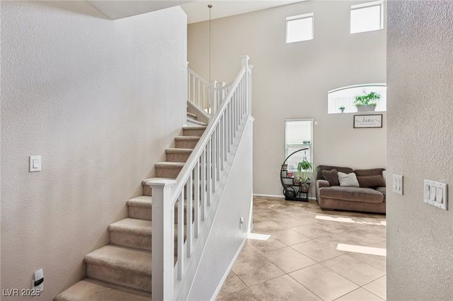 Stairs with a towering ceiling, tile patterned floors, and a textured wall | Image 7