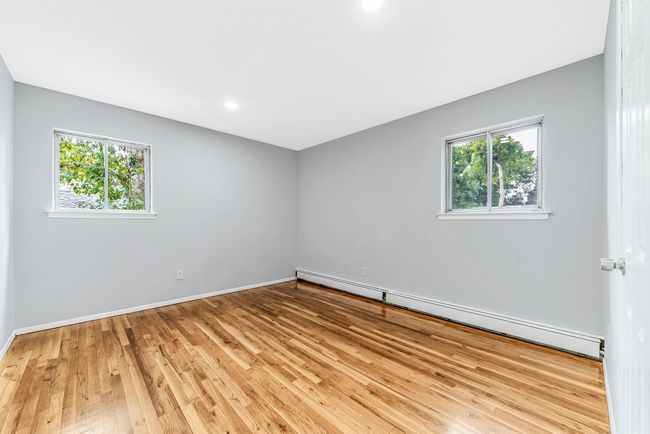 Spare room featuring baseboards, wood finished floors, a healthy amount of sunlight, and a baseboard radiator | Image 11
