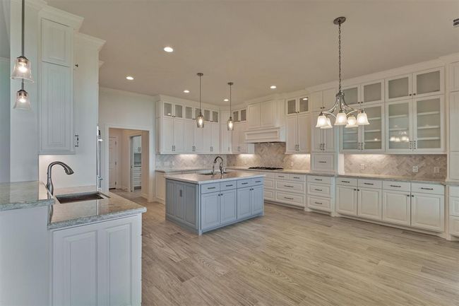 The kitchen and dining area were thoughtfully designed to combine functionality with style. Two sinks provide added convenience, while a mix of glass-front and solid cabinetry, along with an array of drawers, offers versatile and abundant storage options. | Image 13