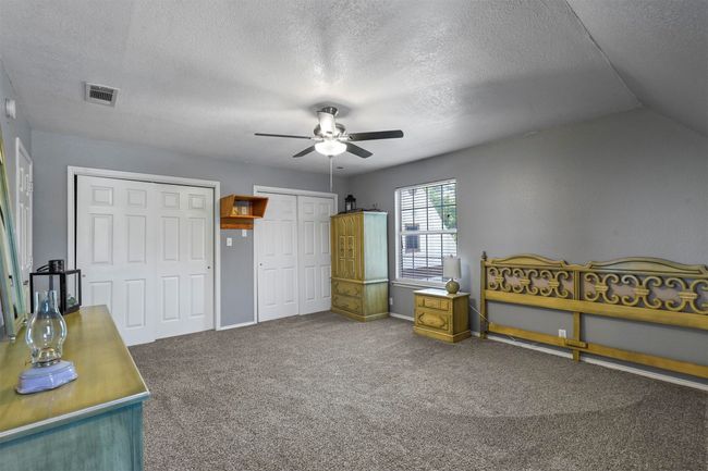 Bedroom with ceiling fan, vaulted ceiling, carpet flooring, two closets, and a textured ceiling | Image 31