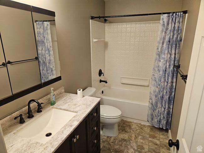 Full bathroom featuring shower / bath combo with shower curtain, vanity, and toilet | Image 54