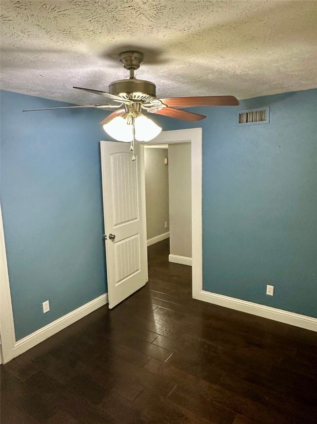 Spare room featuring wood finished floors, a textured ceiling, and a ceiling fan | Image 33