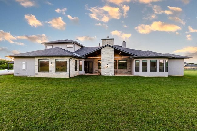 Rear view of property with a patio, a lawn, a chimney, and roof with shingles | Image 26