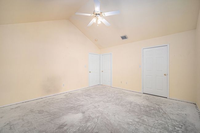 Second Primary Bedroom. Carpet has been removed to reveal concrete floor. Walk-in closet on the right and ensuite bath behind middle door. | Image 15
