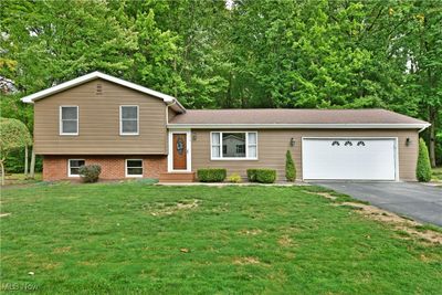 Split level home with a garage and a front lawn | Image 1