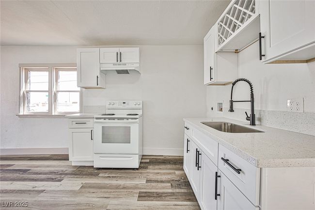 Kitchen with white electric range oven, under cabinet range hood, light wood-style floors, and white cabinets | Image 5