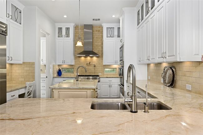 Kitchen with wall chimney range hood, tasteful backsplash, Taj Mahal Quartzite counters, recessed lighting | Image 8