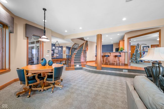 carpeted dining area featuring recessed lighting, a bar, baseboards, and stairs | Image 67