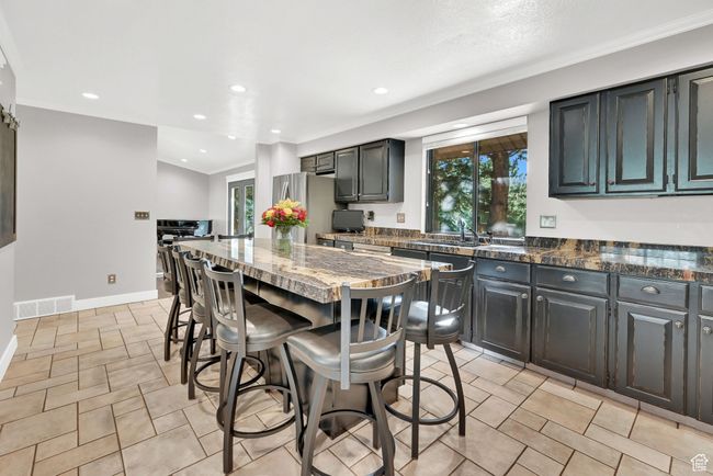 Kitchen featuring dark stone countertops, a center island, a breakfast bar area, and sink | Image 13