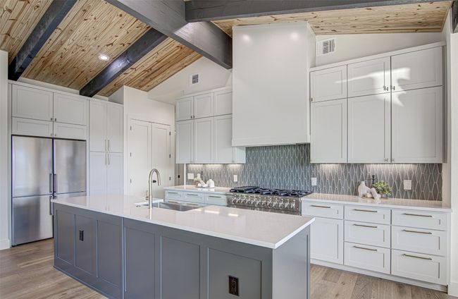 Kitchen with high quality appliances, a sink, light countertops, white cabinetry, and light wood-style flooring | Image 5