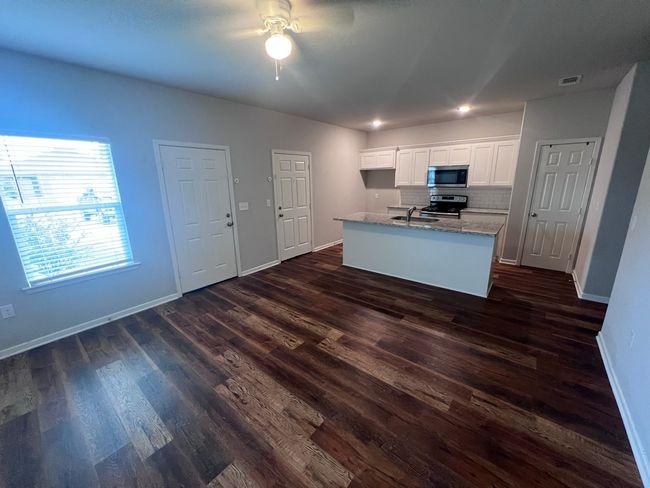 Kitchen featuring stainless steel appliances, a sink, a ceiling fan, baseboards, and light stone countertops | Image 14