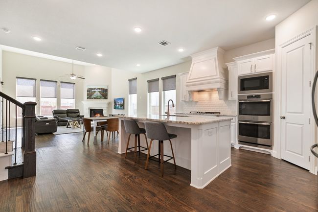 Kitchen featuring double oven, built in microwave, visible vents, a warm lit fireplace, and custom exhaust hood | Image 11